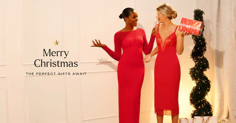 Two women in elegant red dresses, one holding a gift, with a festive 